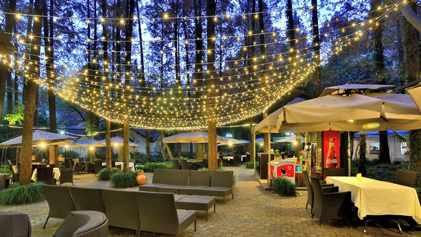 An outdoor patio area with string lights, wicker furniture, and umbrellas. - Lotus Glade Hotel (Hangzhou)