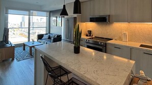 A modern kitchen with a large island, stainless steel appliances, and pendant lighting. - Modern 1BR Apt with Stunning Views and Pool Access (Toronto)