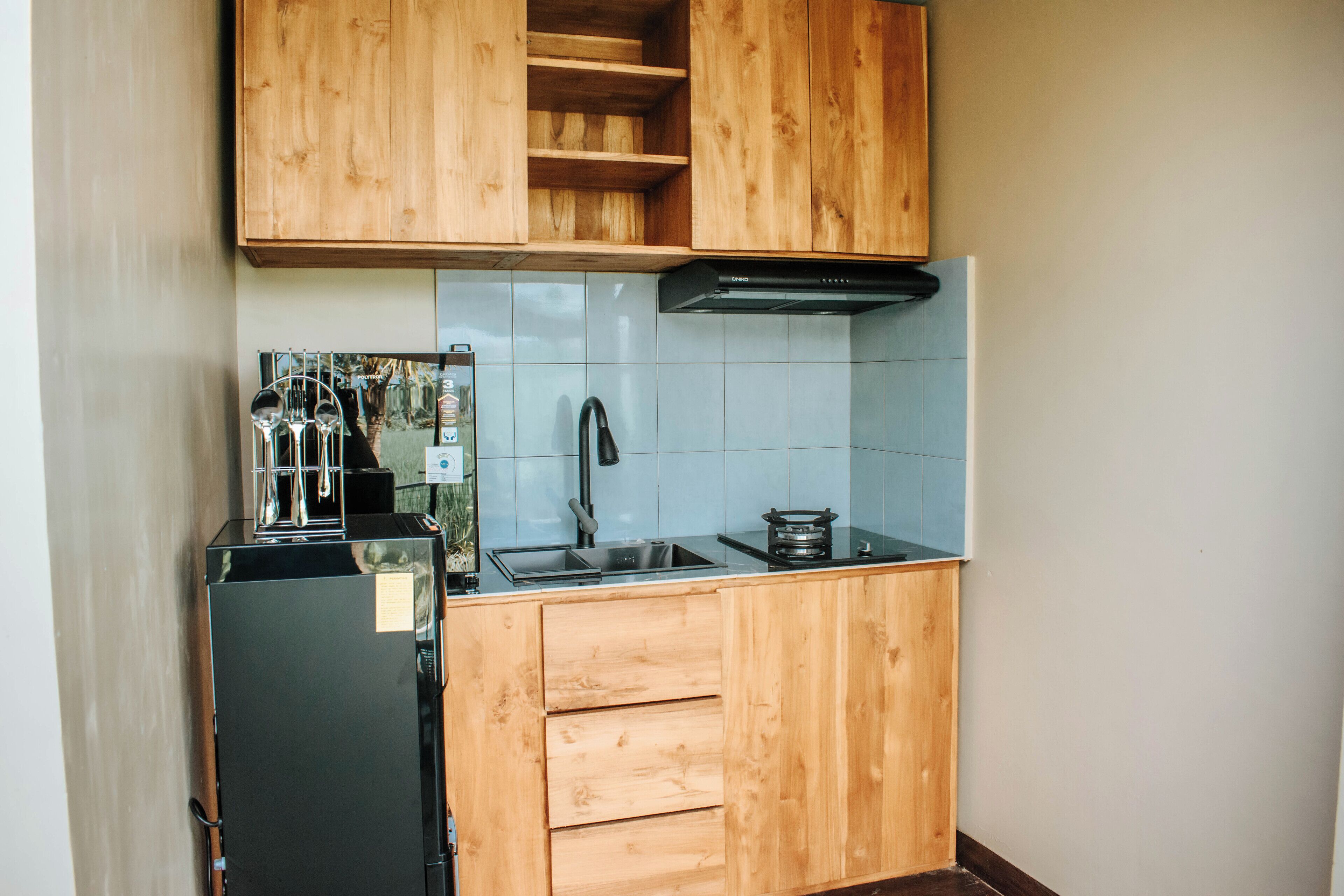 A compact kitchen with wooden cabinets, a black refrigerator, a sink, and a stove.