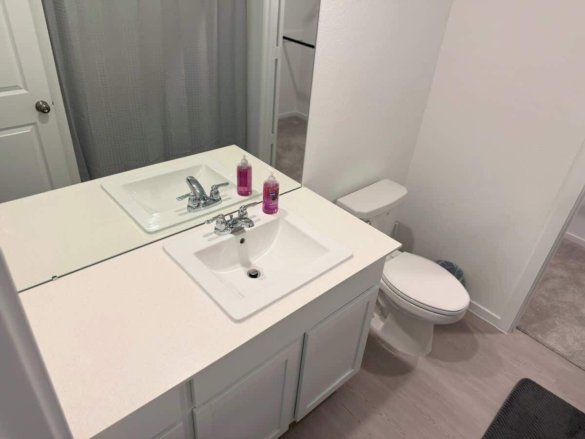 Un baño con lavamanos, espejo y retrete blancos.