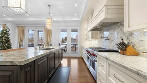 A modern kitchen with dark wood cabinets, a marble countertop, and a large island.