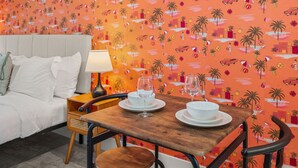 Een kamer met een bed, een tafel gedekt met witte servies en glazen, en een wand met oranje dessin.