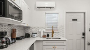 Een moderne keuken met witte kasten, een magnetron, een koffiezetapparaat en een spoelbak.