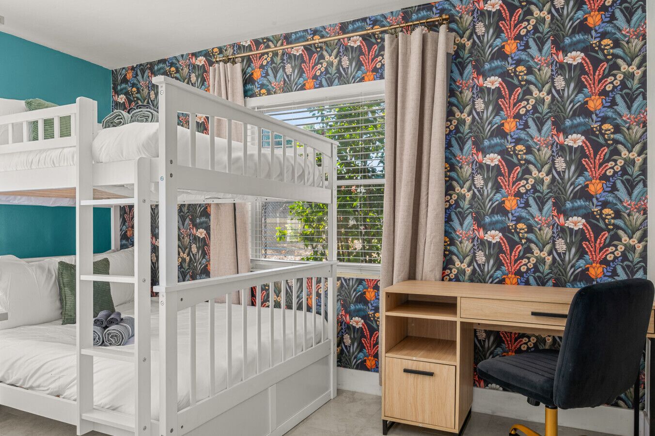 A room with bunk beds, a desk, and a chair.
