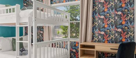 A room with bunk beds, a desk, and a chair.