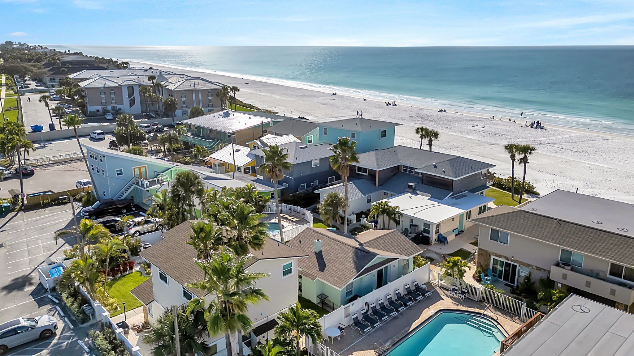 A coastal residential area with houses, a swimming pool, and a beach.
