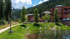 Un hotel sul lago con posti a sedere all'aperto, uno stagno e montagne sullo sfondo.