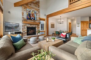A spacious living room with a fireplace, a television, and a dining area. - Lakota Antlers 108 | Private Hot Tub | Slope Views (Winter Park)