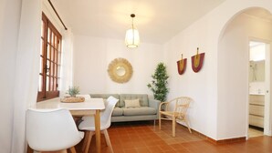 Een eetgedeelte met een tafel en stoelen, een bank en een hanglamp.