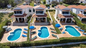 Un complejo residencial con varias casas, una piscina central y zonas de estar al aire libre.
