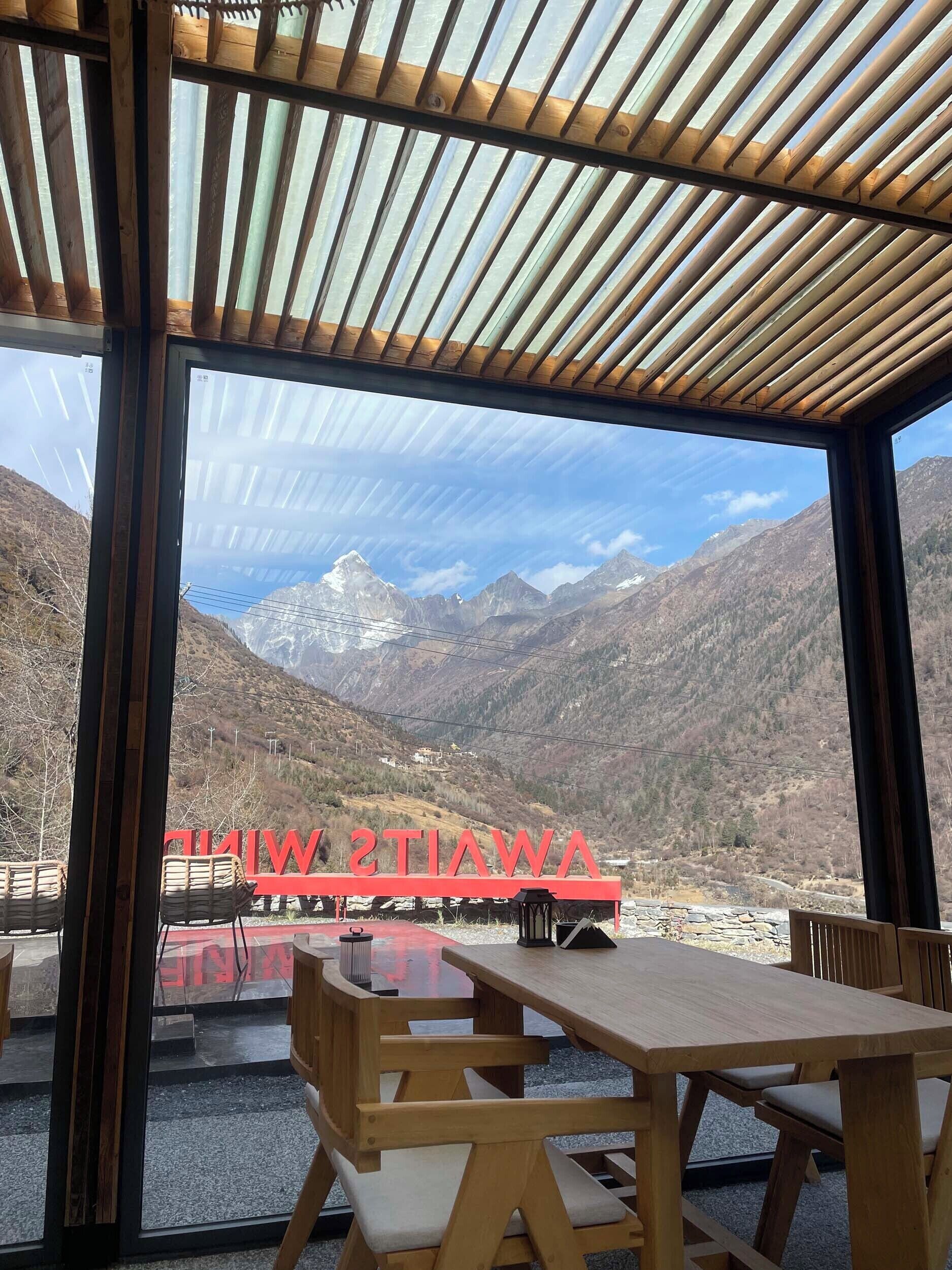 Ein Restaurant mit Blick auf Berge, Holzmöbeln und einem roten Schild.