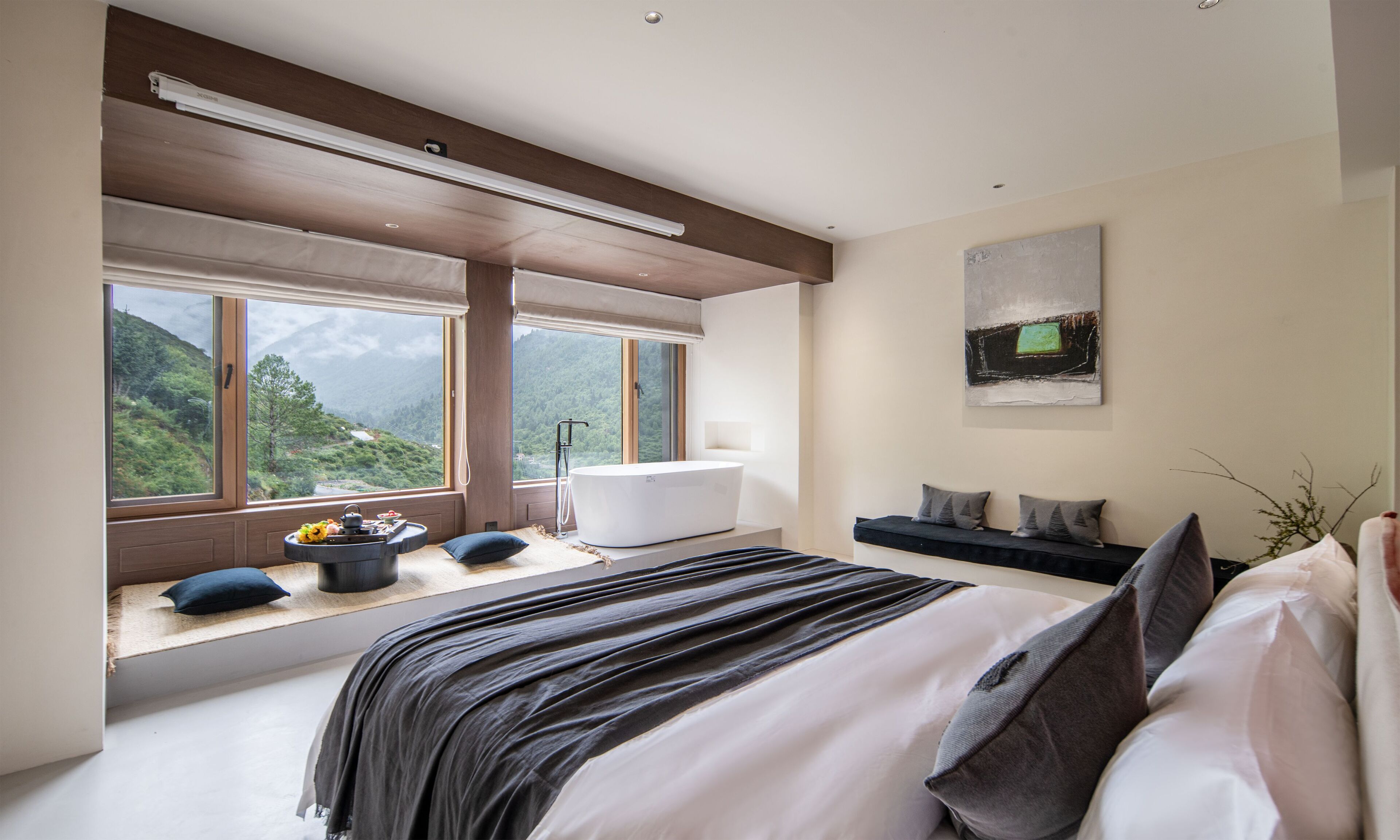 Une chambre moderne dotée d’un grand lit, d’une baignoire et offrant une vue sur un paysage montagneux.