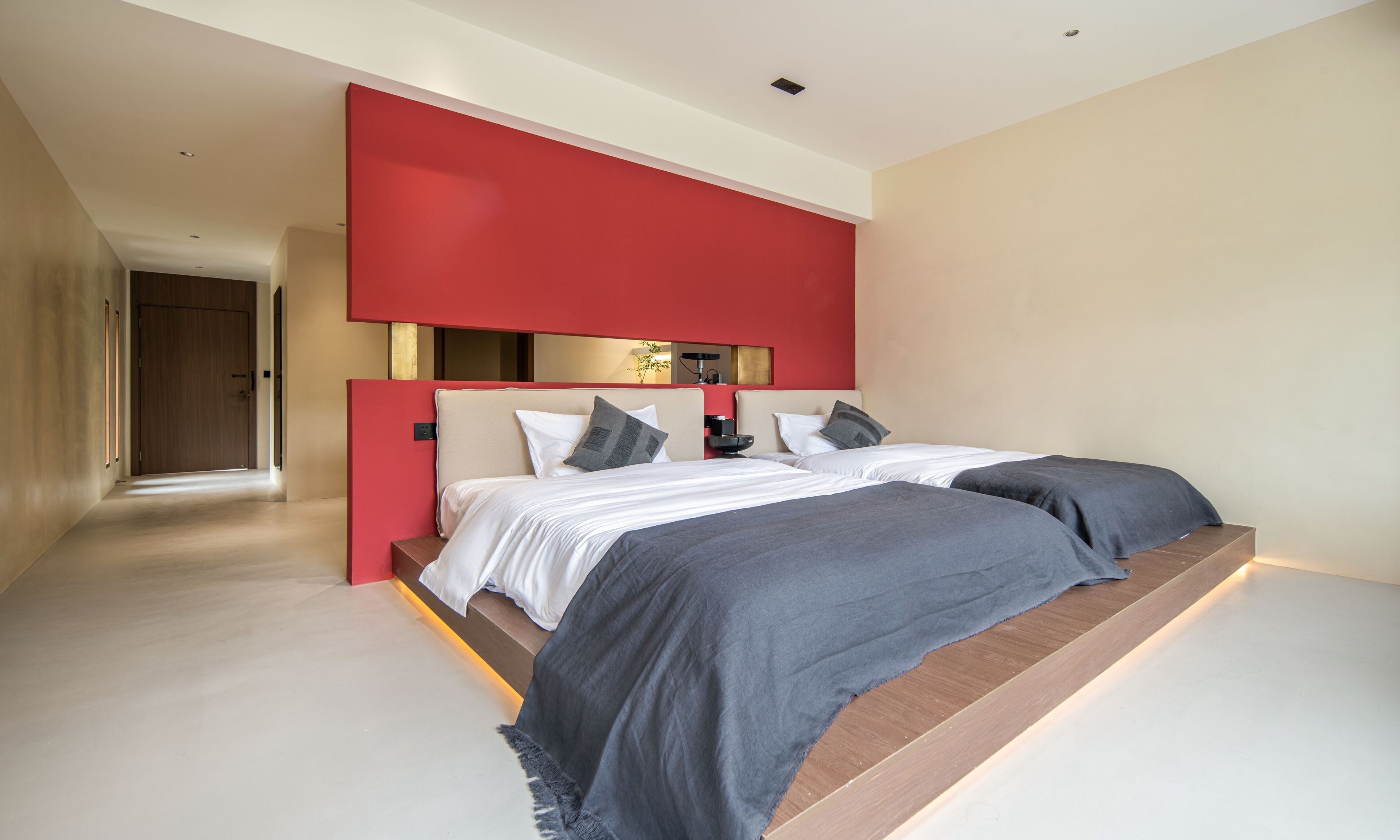 Un dormitorio moderno con una cama grande, una pared de acento roja y un diseño minimalista.