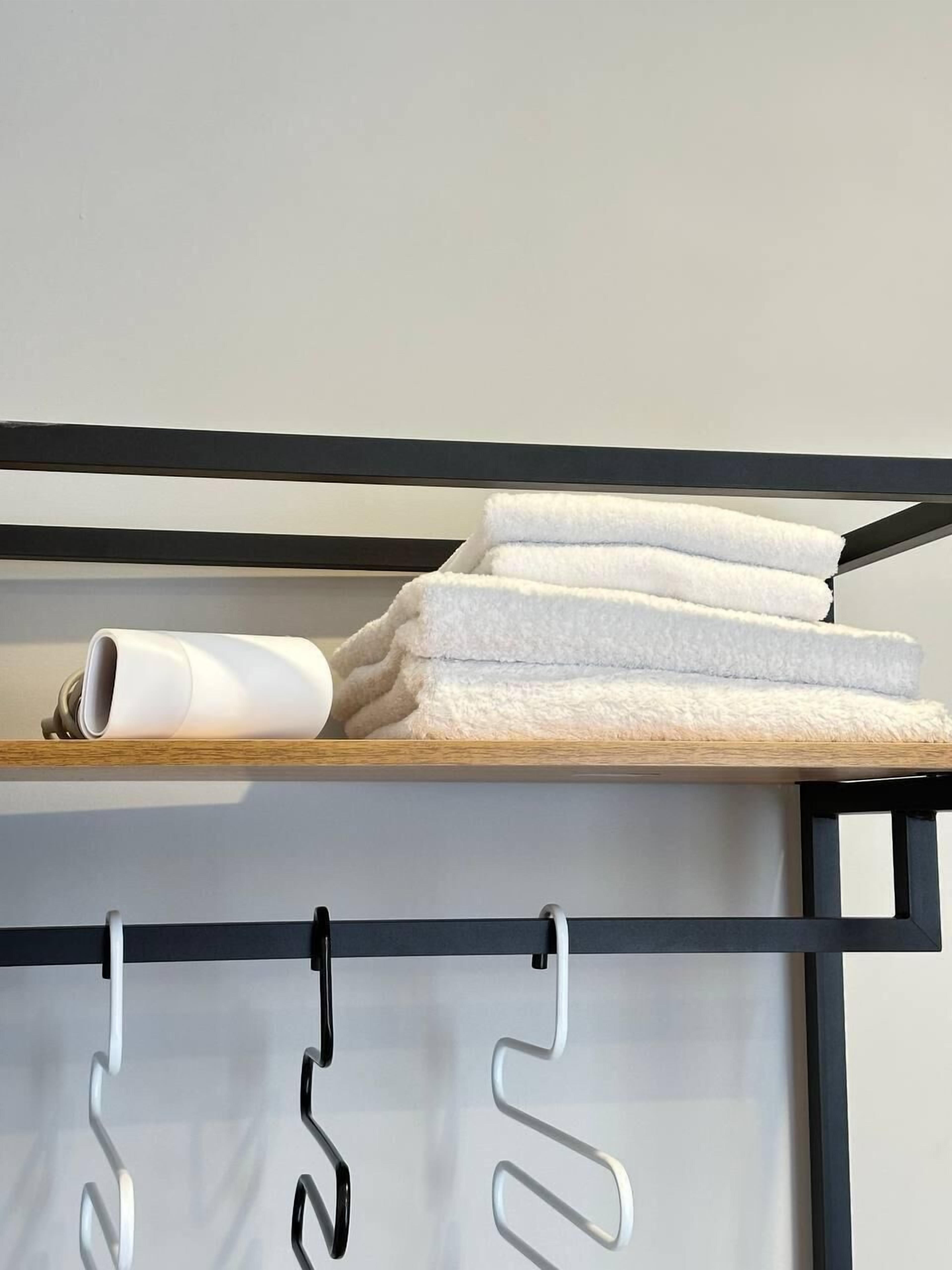 A modern bathroom with a towel rack holding folded towels and a white showerhead.