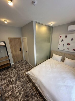 A hotel room with a bed, a wardrobe, a door, and a patterned carpet.