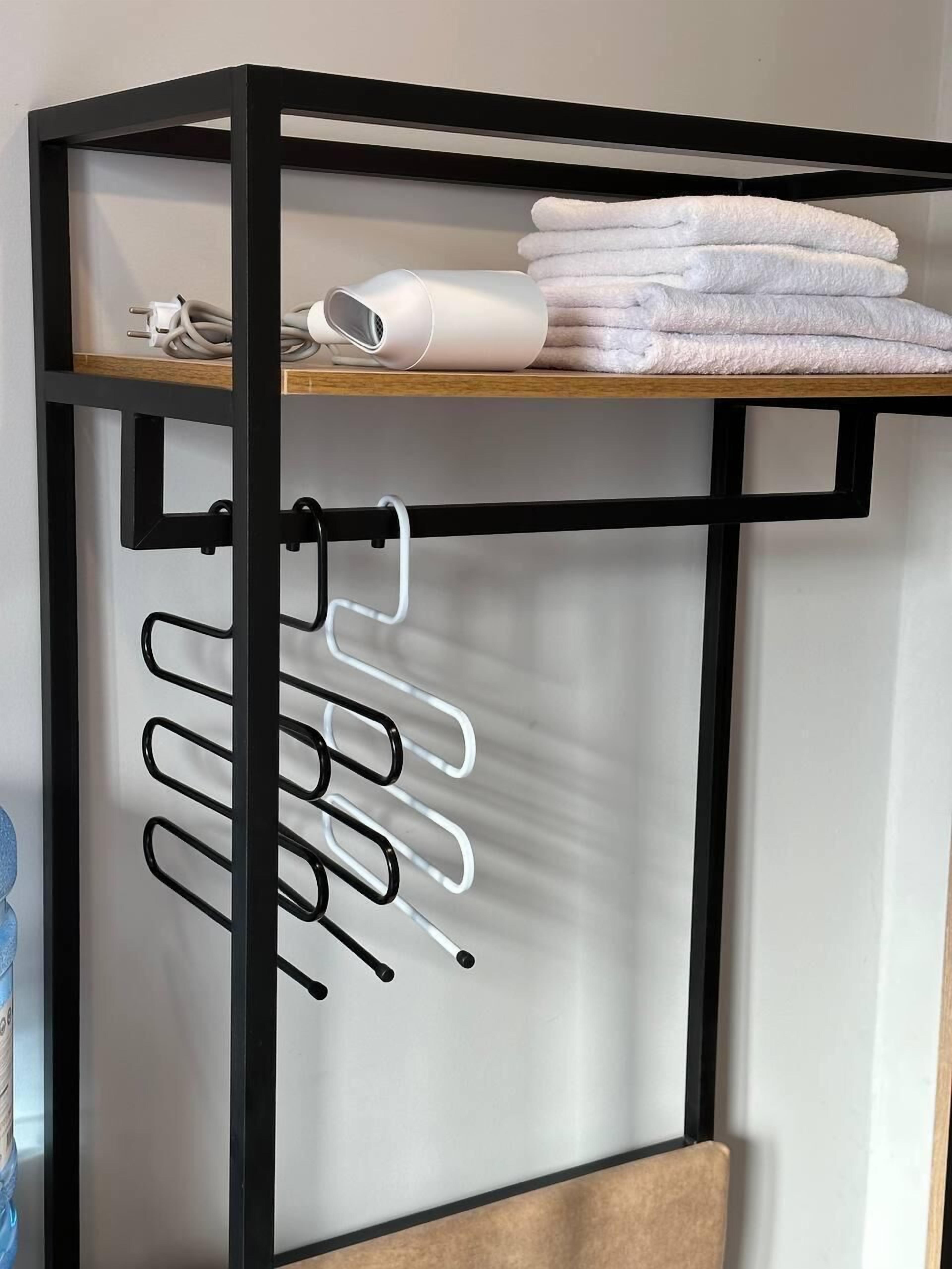 Ein Bett mit Metallgestell und Ablagefläche darüber, auf der Handtücher und ein Fön liegen.