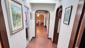 Ein Flur mit weißen, strukturierten Wänden, gerahmten Kunstwerken und Holzboden.