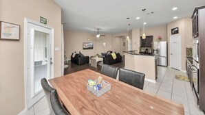 Una cocina moderna con una isla central, un comedor con mesa de madera y una sala de estar con sofá y mesa baja.