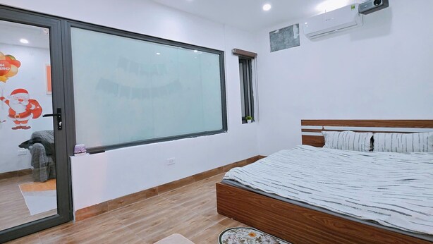 Ein modernes Schlafzimmer mit einem großen Bett, einer Schiebeglastür und einem an der Wand montierten Projektor.