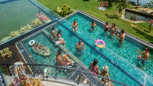 A swimming pool with clear water, surrounded by a grassy area and trees, with a view of a lake and hills in the background. - ZEN Koggala Lakefront Boutique Retreat (Harumalgoda)