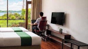 A hotel room with a large bed, a desk with a chair, a TV, and a view of a lake. - ZEN Koggala Lakefront Boutique Retreat (Harumalgoda)