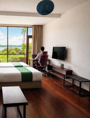 Habitación de hotel con una cama grande, un escritorio con silla, televisión y vista a un lago.