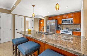 Eine moderne Küche mit Granit Arbeitsplatten, Edelstahlgeräten und Holzschränken.