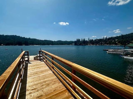 A wooden pier extending into a calm lake with a clear sky.