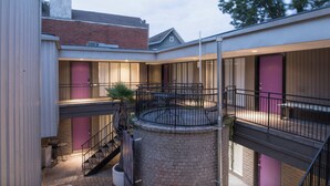 Un edificio a più livelli con balconi, un cortile interno e un muro in mattoni.