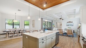 A modern kitchen with a central island, wooden flooring, and pendant lighting. - Family Beach Oasis w/ Heated Pool, Spa & Guest House (Bonita Springs)