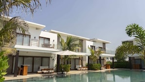 Un hotel moderno con piscina, zona de estar exterior y palmeras.