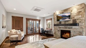 Un dormitorio con chimenea de piedra, una cama grande, un sofá y un escritorio con una silla.