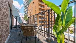 A balcony with wicker chairs and a potted plant, overlooking a modern building with multiple balconies. - Have a great time on the top floor with a view of Tsutenkaku Tower from the terrace in the heart of Osaka. 3 minutes from Kuromon Market!  Max. 8 people OK (Osaka city Naniwa-Ward Shimodera)