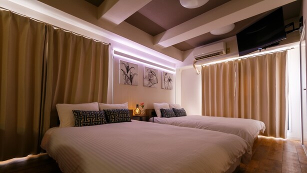 A double bed with patterned pillows, a bedside table with a vase, and wall art. - Have a great time on the top floor with a view of Tsutenkaku Tower from the terrace in the heart of Osaka. 3 minutes from Kuromon Market!  Max. 8 people OK (Osaka city Naniwa-Ward Shimodera)