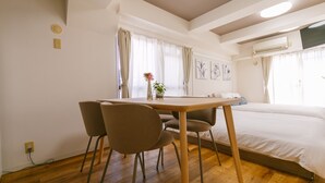 A hotel room with a wooden floor, a bed, a table with chairs, and a window with curtains. - Have a great time on the top floor with a view of Tsutenkaku Tower from the terrace in the heart of Osaka. 3 minutes from Kuromon Market!  Max. 8 people OK (Osaka city Naniwa-Ward Shimodera)