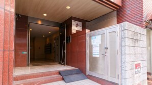 A building entrance with a metal door, a ramp, and a sign on the wall. - Have a great time on the top floor with a view of Tsutenkaku Tower from the terrace in the heart of Osaka. 3 minutes from Kuromon Market!  Max. 8 people OK (Osaka city Naniwa-Ward Shimodera)