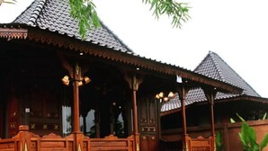 Une maison traditionnelle en bois, dotée d’un porche et d’un toit recouvert de tuiles.