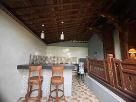 Una cocina con salpicadero de azulejos, taburetes de madera, un refrigerador y una barandilla de madera.