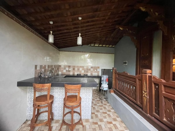 Een keuken met een bar, twee houten barstoelen, een waterdispenser en een houten leuning.