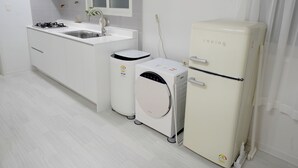 Una cocina compacta con armarios blancos, un lavamanos, una estufa, lavadora y refrigerador.
