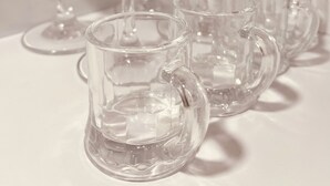 Una colección de cristalería transparente, incluyendo copas de vino y tazas, dispuestas sobre una superficie blanca.