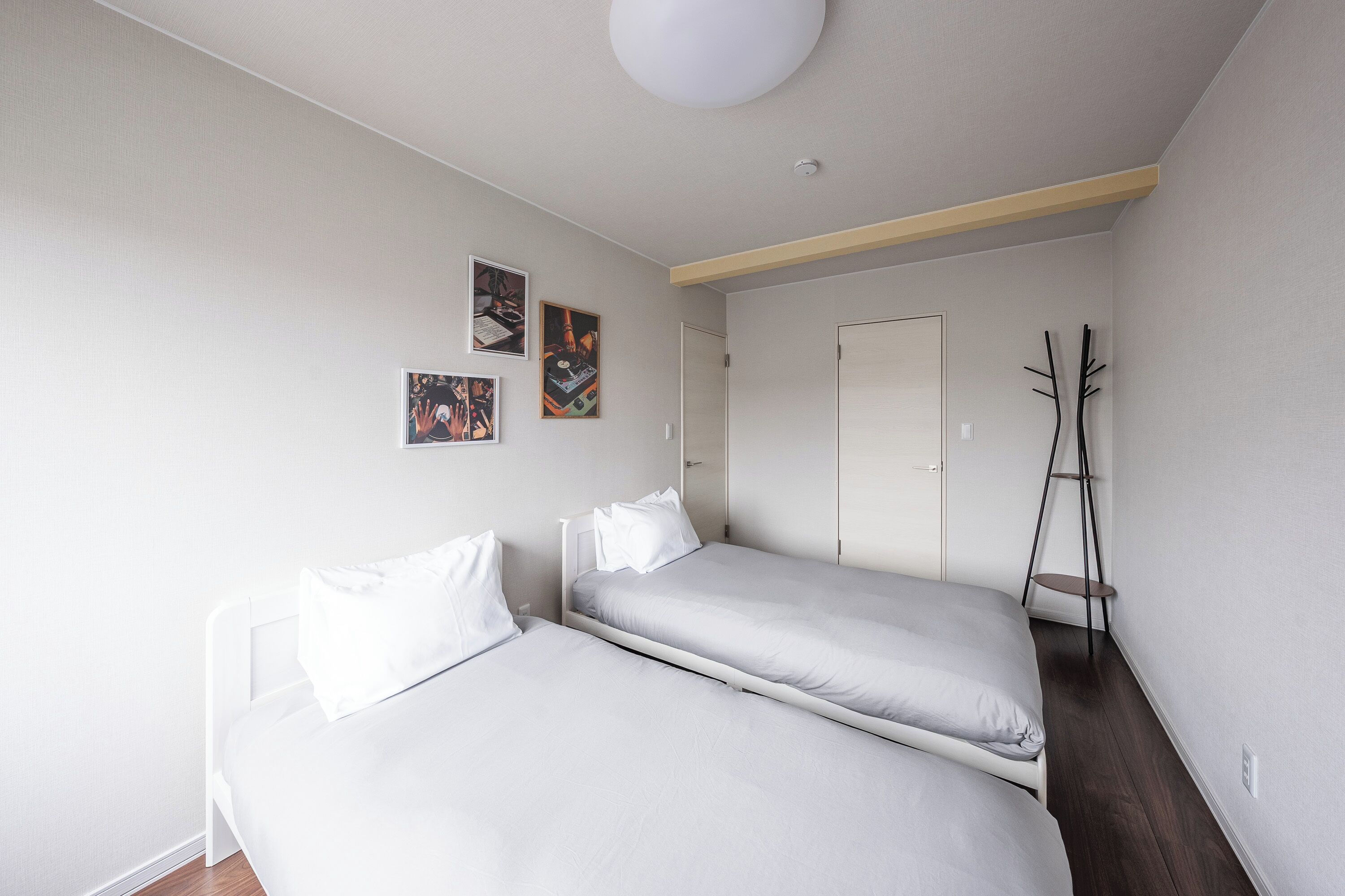 A bedroom with two beds, a wardrobe, and a coat rack.
