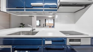 A modern kitchen with blue cabinets, a white countertop, and a built-in oven. - CALM FOREST (Asahikawa)