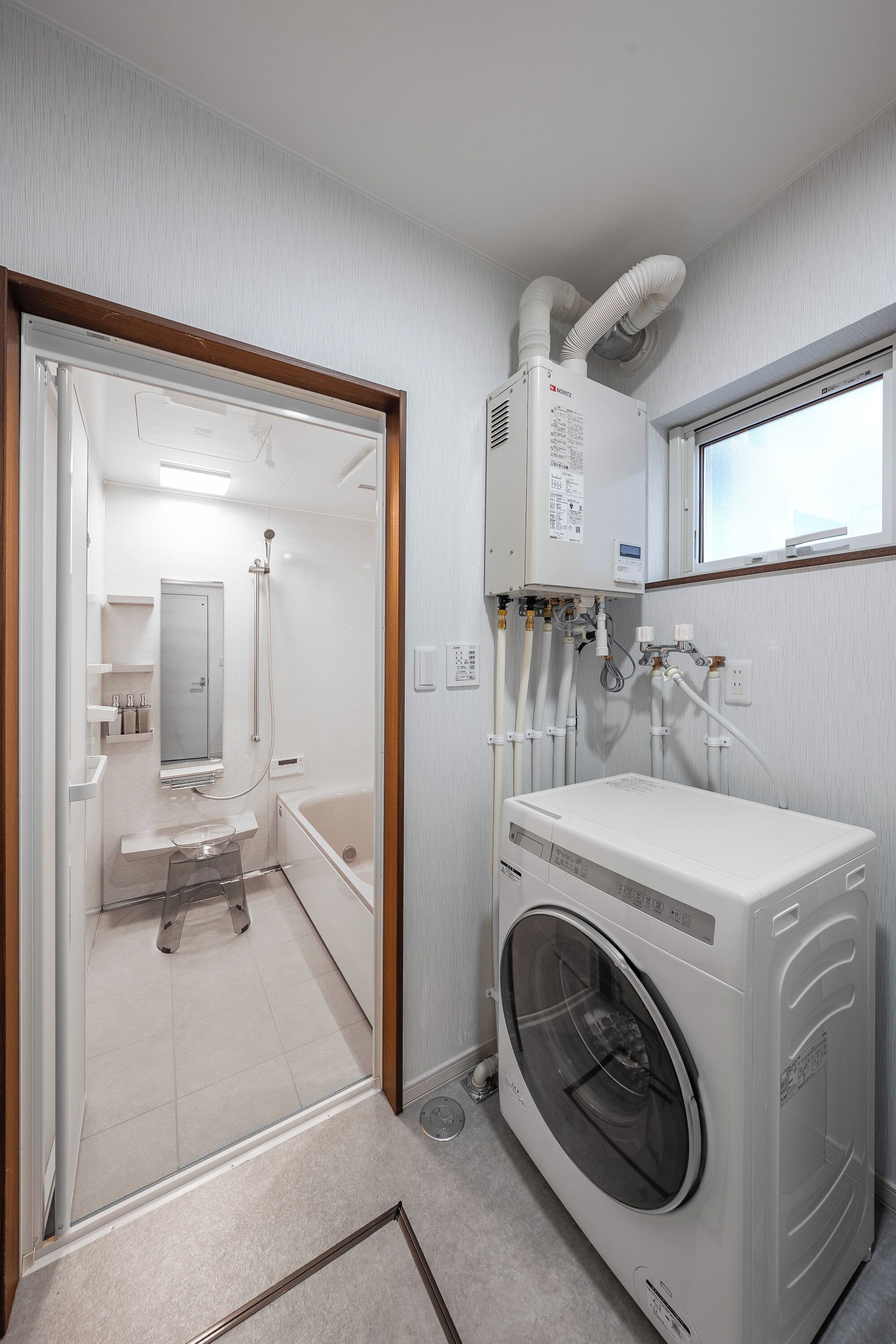 A compact, modern bathroom with a built-in washer and dryer, a shower, and a toilet.