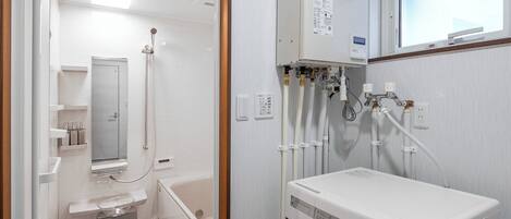 A compact, modern bathroom with a built-in washer and dryer, a shower, and a toilet.
