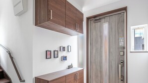 A modern interior with a wooden staircase, a hallway with a door, and a tiled floor. - CALM FOREST (Asahikawa)