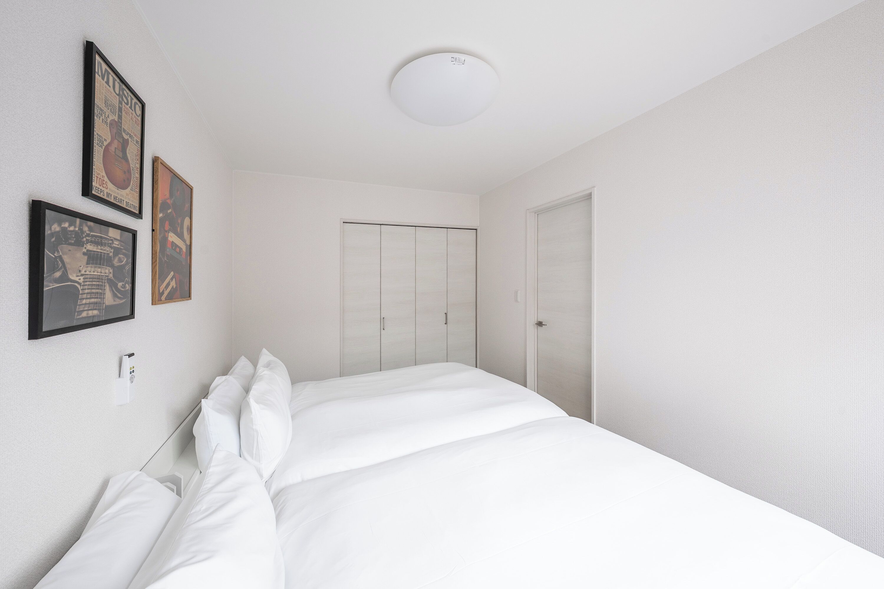 Una habitación de hotel con una cama bien hecha, un armario y tres carteles enmarcados en la pared.