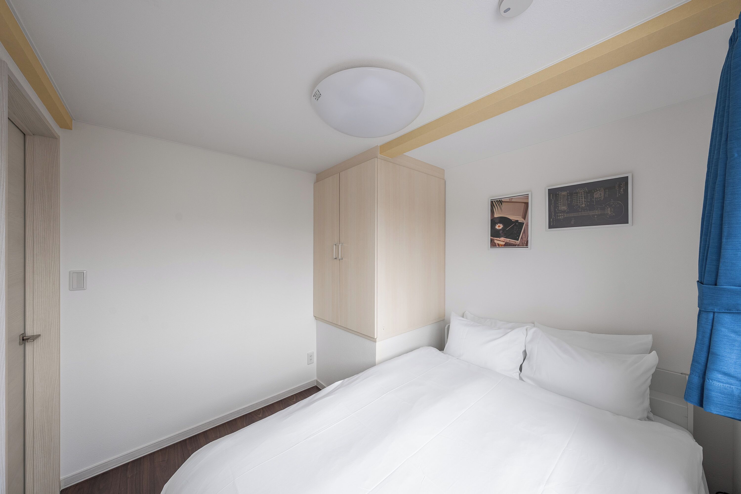 Une chambre à coucher avec un lit, une armoire et deux tableaux encadrés accrochés au mur.