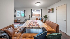 A modern living room with a brown leather sofa, a wooden coffee table, and a large window with curtains. - CALM FOREST (Asahikawa)