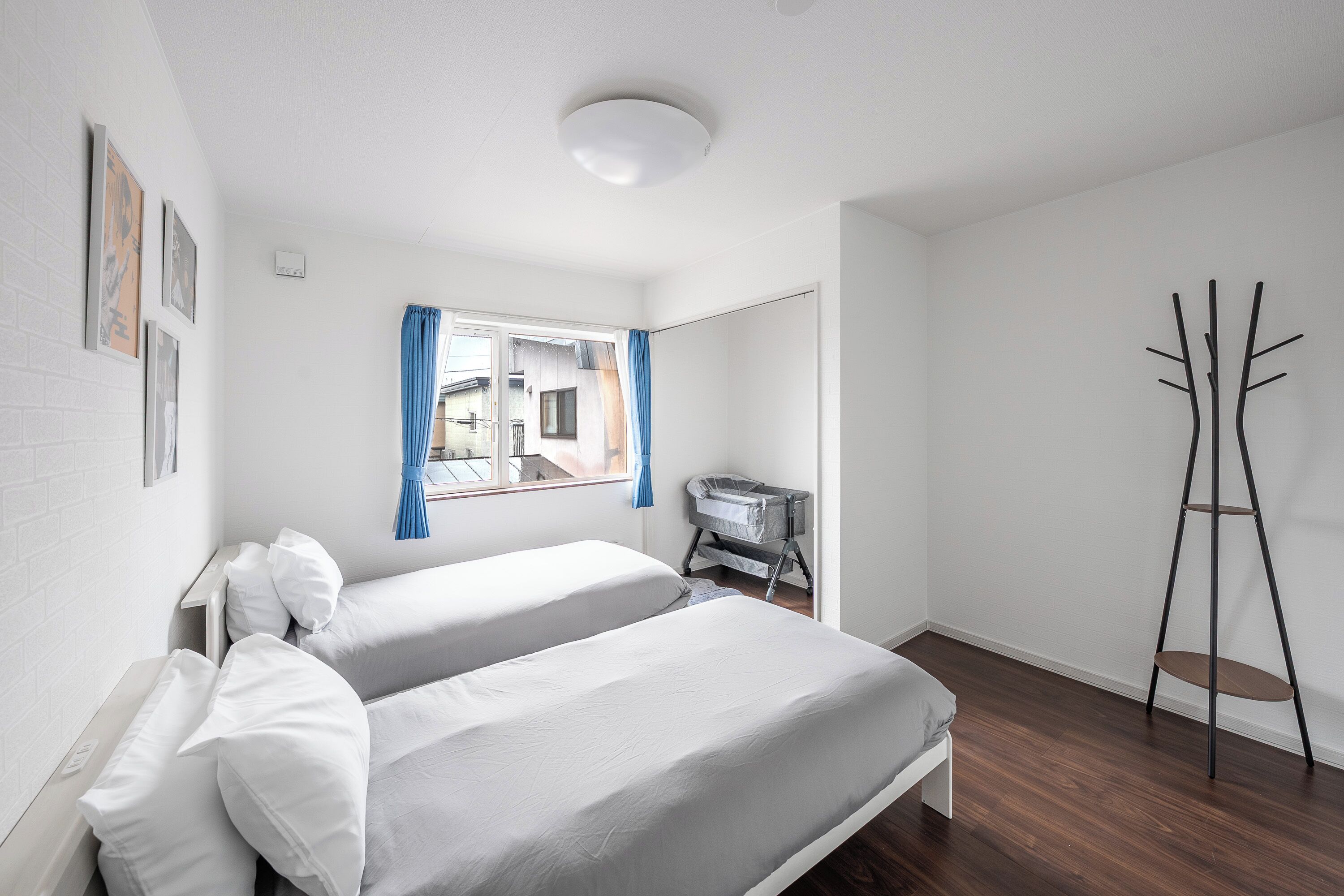 Une chambre d’hôtel avec deux lits, une fenêtre avec des rideaux, un porte-manteau et une vue sur l’extérieur.